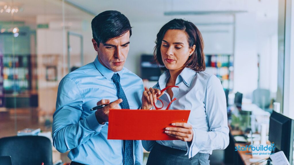 two employees talking about work while using a tablet device